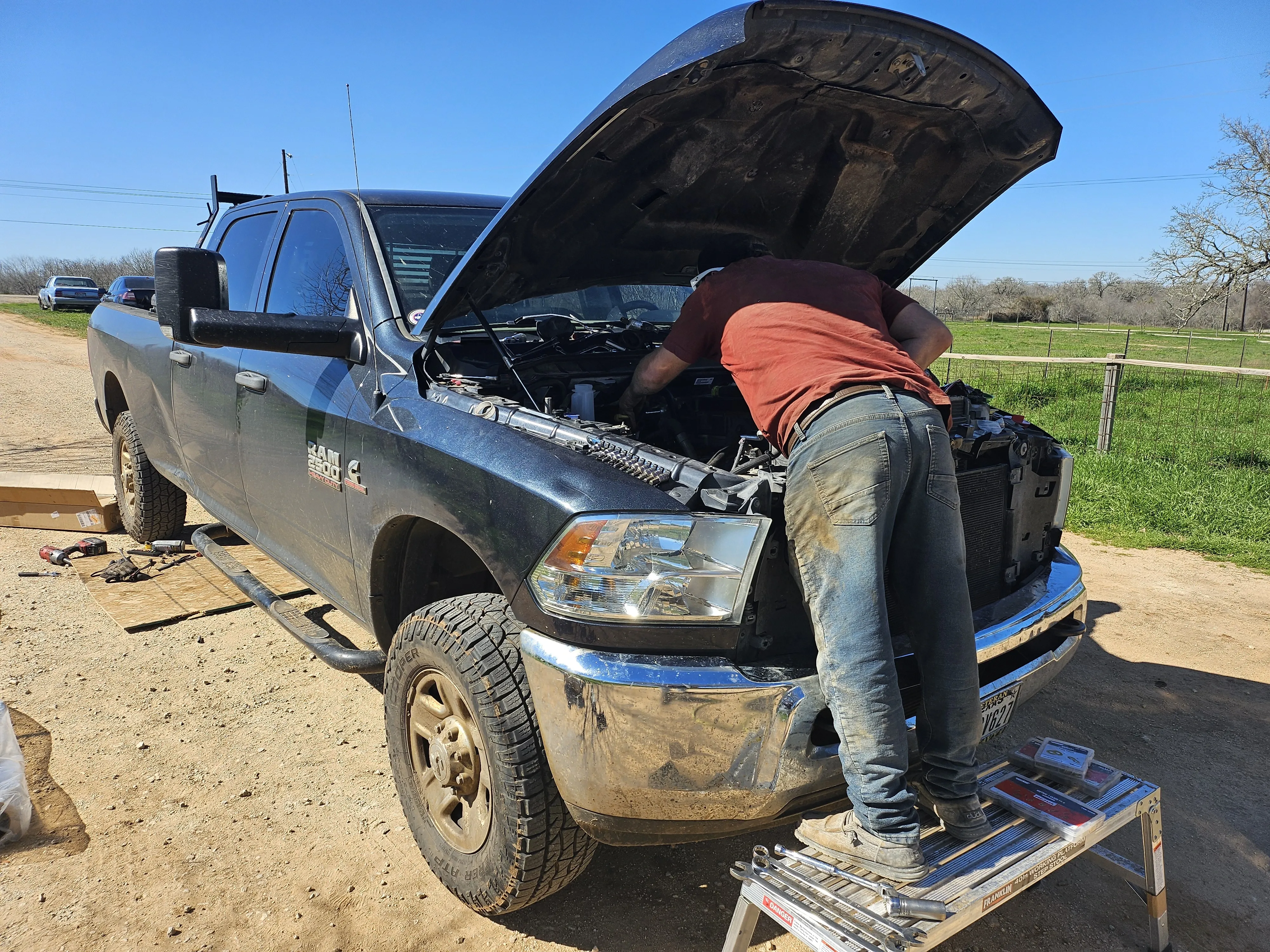 Mechanic leaning into the engine compartment of a pickup truck, working on repairs.