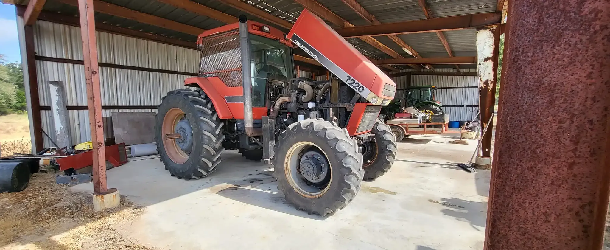 SIde view of a large red tractor with engine compartment open.