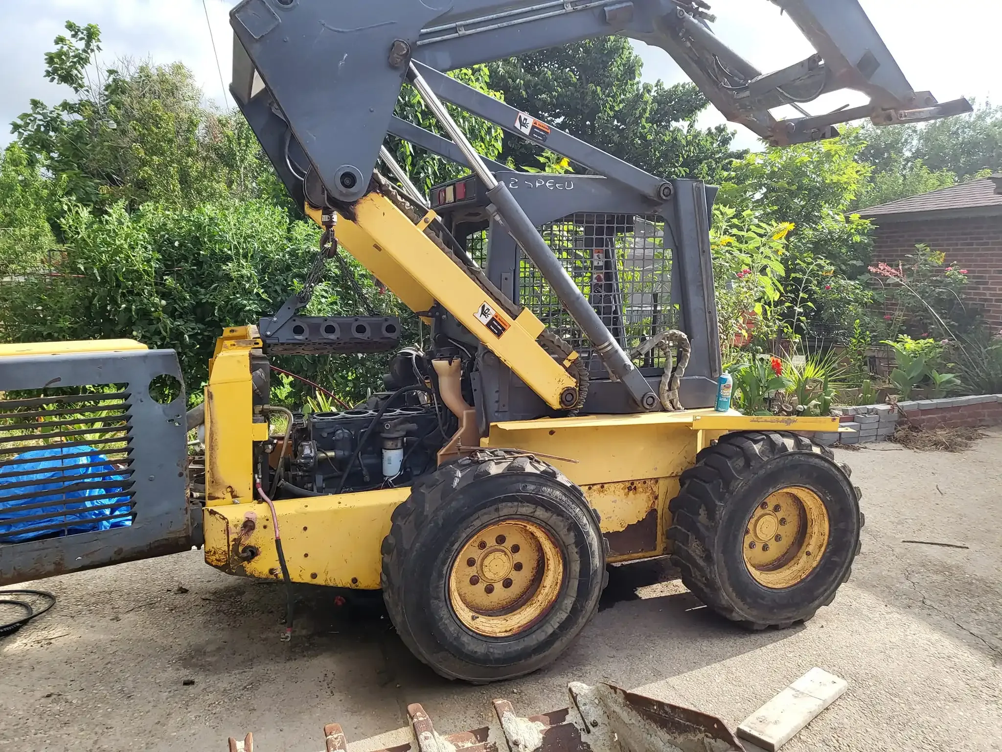 Heavy equipment engine head being lifted from engine compartment.