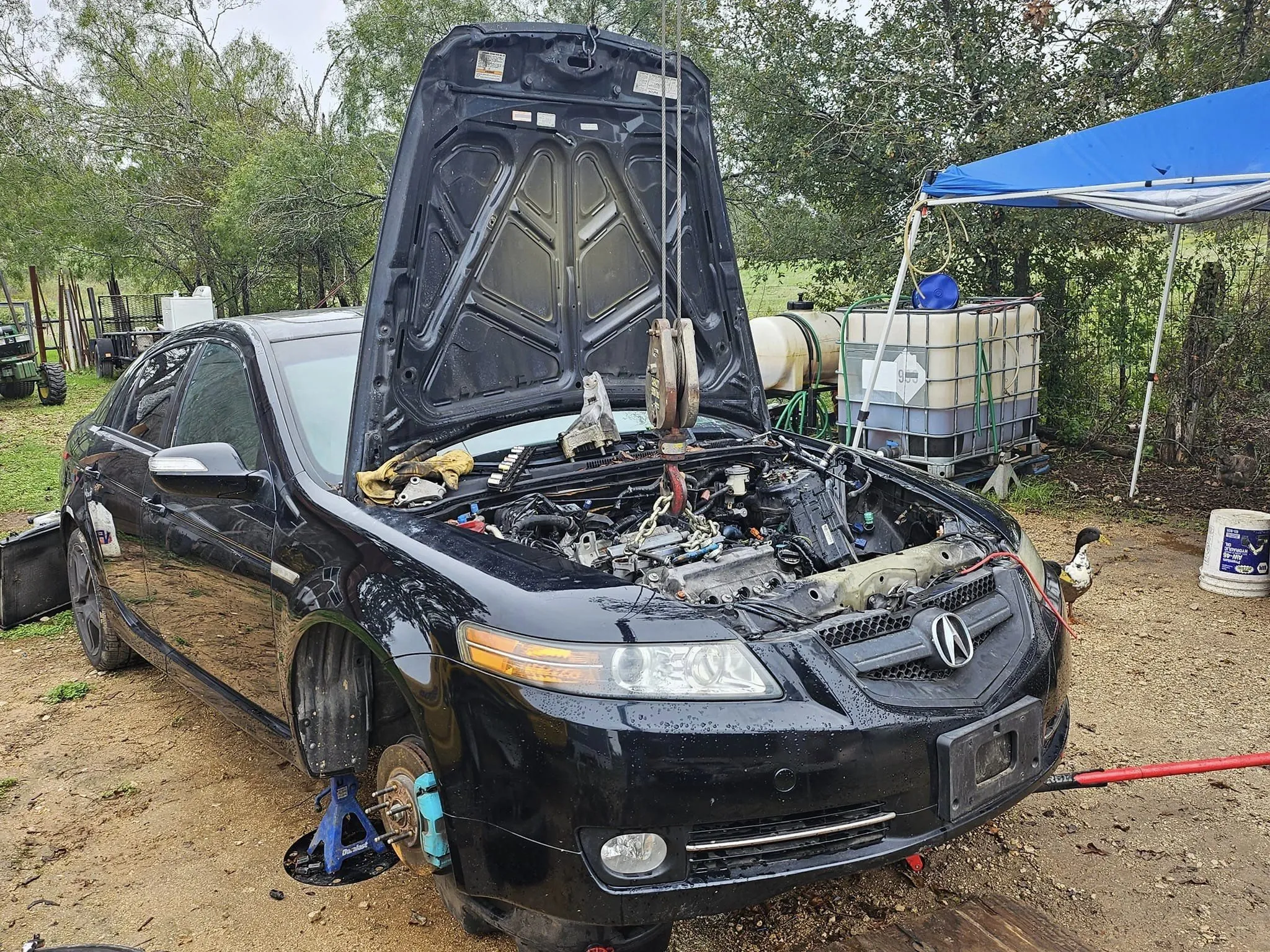 Black car with its hood open, revealing the engine compartment, undergoing repair.